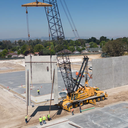 Drone Photograph of Yellow Crain Lifting Concrete Tilt-Up Wall - FAA Certified Drone Photographer - Atascadero Drone Photographer - Real Estate Drone Photography - Studio 101 West Drone Photographer Construction Progress - Drone Photography - Cement Tilt-Up wall - Aerial Photography Construction Site - Crane holding Cement Wall in Air - Drone Construction Progress Photography - Studio 101 West Photography